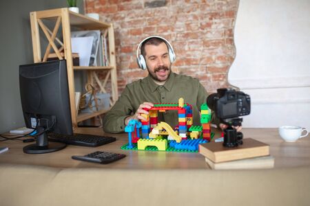 Man giving online lesson with constructor at home. Recording teachers tutorial on camera for kids....