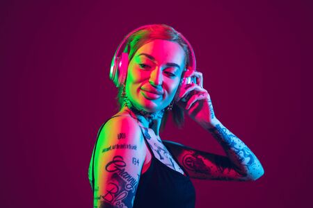 Listening to music, dancing with wireless headphones. Portrait of young caucasian woman on purple...