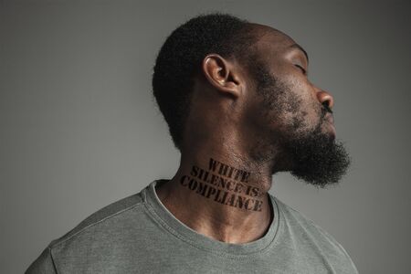 Close up black man tired of racial discrimination has tattooed slogan white silence is compliance on his neck. Concept of human rights, equality, justice, problem of violence and racism. Eyes closed.の写真素材