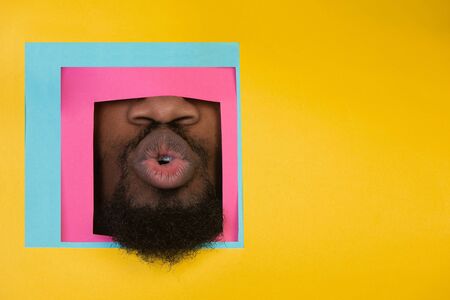 Kiss. Mouth of emotional african-american man peeks throught square in yellow background. Trendy...