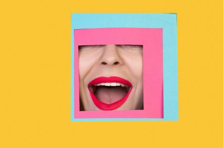 Astonished. Face of emotional caucasian woman peeks throught square in yellow background. Trendy geometrical style, copyspace. Vibrant colors. Sales, confines, finance and business concept. Framing.の写真素材