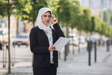 Paperwork. Beautiful muslim successful businesswoman portrait, confident happy CEO, leader, boss or manager. Using devices, gadgets, working on the go, looks busy. Charming model. Inclusive, diversity.の写真素材