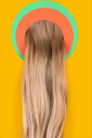 Female long blonde hair peek throught circle in yellow background. Trendy geometrical style, copyspace. Vibrant colors. Sales, proposal, finance and business, fashion concept. Salon treatment.の写真素材