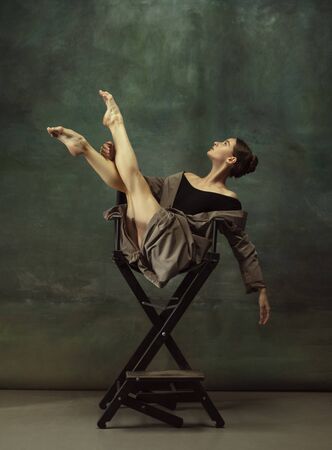 Beautiful portrait, dreamful. Graceful classic ballerina dancing, posing isolated on dark studio background. Stylish trench coat. Grace, movement, action and motion concept. Looks weightless, flexible.の写真素材