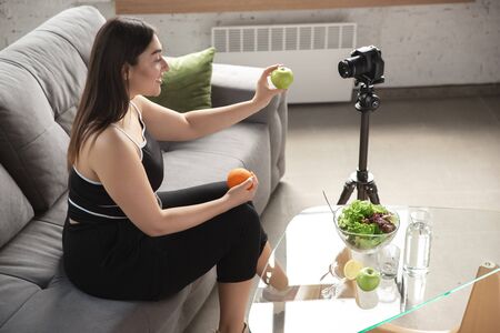 Caucasian blogger, woman make vlog how to diet and lost weight, be body positive, healthy eating. Using camera recording her organic and tasty recipes. Lifestyle influencer, wellness concept.の写真素材