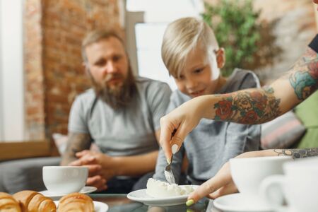 Best day. Happy family at home spending time together. Having fun, look cheerful and lovely. Mother, father and son eating sweets, talking, laughting. Childhood, domestic life, togetherness concept.の写真素材