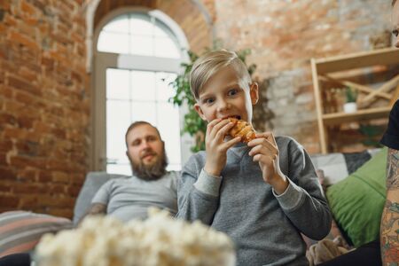 Happy family at home spending time together. Having fun, look cheerful and lovely. Mother, father and son eating croissants, talking, laughting. Childhood, domestic life, togetherness concept.の写真素材