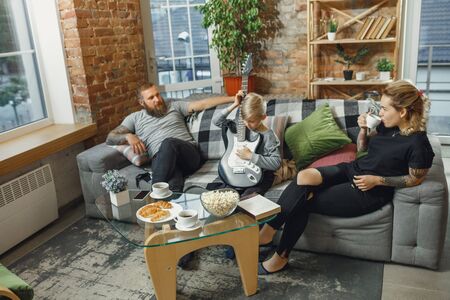 Happy family at home spending time together. Having fun, look cheerful and lovely. Mother, father and son playing guitar, talking, singing. Childhood, domestic life, togetherness concept.の写真素材