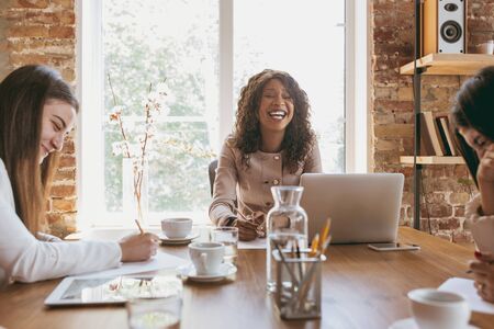 Young business woman in modern office with team. Creative meeting, tasks giving. Smiling, delighted, teamwork. Concept of finance, business, girl power, inclusion, diversity, feminism Discussionの写真素材