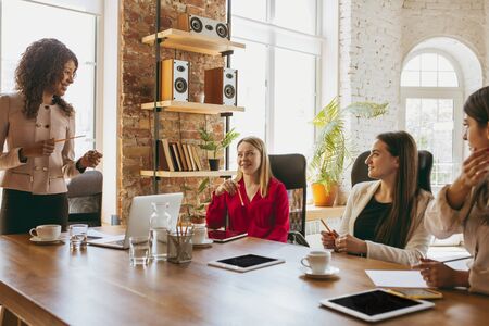 Young caucasian business woman in modern office with team. Creative meeting, tasks giving. Women in front-office working. Concept of finance, business, girl power, inclusion, diversity, feminism.の写真素材