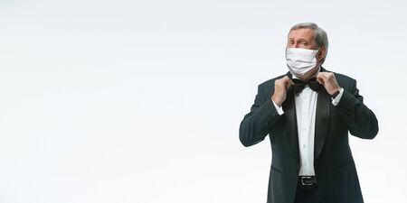 We are open. Elegance senior man waiter in protective face mask on white background. Flyer with copyspace. Cafe, restaurant opening. Safety during coronavirus pandemic. Taking care of guests, clients.の写真素材