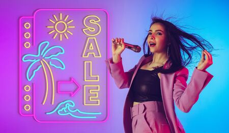 Portrait of woman singer on gradient studio background in neon with sign SALE. Beautiful female...