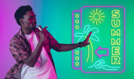 Young musician, party host singing on gradient studio background in neon with sign SUMMER. Concept...