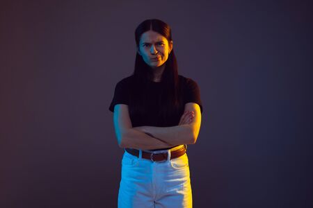 Doubts, thinking. Caucasian young womans portrait on dark studio background in neon. Beautiful...