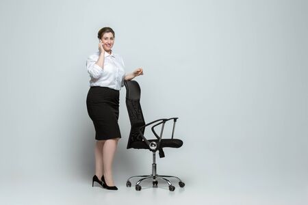 Happy. Young woman in office attire. Bodypositive female character, feminism, loving herself, beauty concept. Plus size businesswoman on gray background. Boss, beautiful. Inclusion, diversity.の写真素材