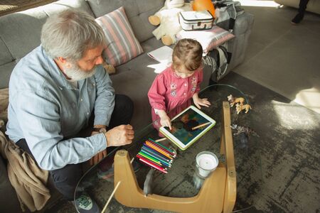 Grandfather and grandchild playing together at home. Happiness, family, relathionship, learning and...