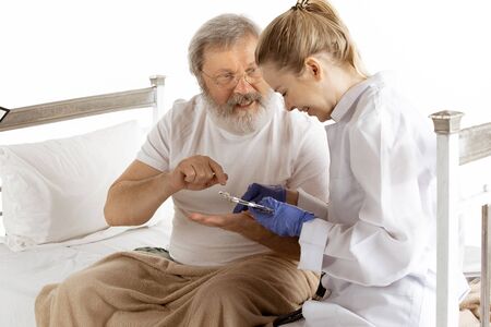 Elderly old man recovering in hospital bed isolated on white background. Getting care and treatment....