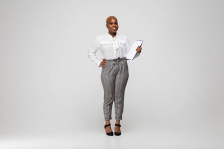 Paperwork. Young woman in office attire. Bodypositive female character, feminism, loving herself, beauty concept. Plus size businesswoman on gray background. Boss, beautiful. Inclusion, diversity.の写真素材