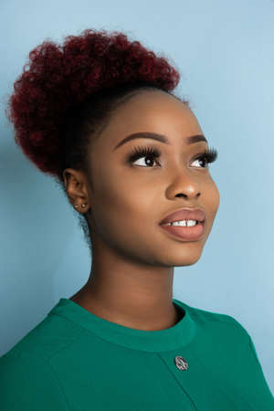 Calm and beautiful. African-american young womans close up portrait on blue studio background....