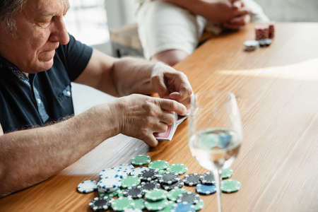 Exciting. Happy mature man playing cards and drinking wine with friends. Looks delighted, excited. Caucasian man gambling at home. Sincere emotions, wellbeing, facial expression concept. Good old age.の写真素材