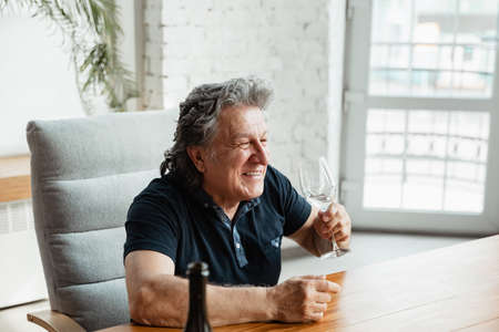 Exciting. Happy mature man playing cards and drinking wine with friends. Looks delighted, excited. Caucasian man gambling at home. Sincere emotions, wellbeing, facial expression concept. Good old age.の写真素材