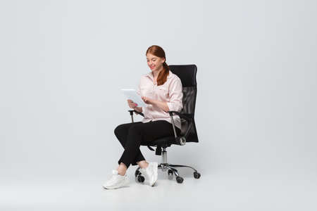 Working with tablet. Young woman in casual wear on white background. Bodypositive character,...