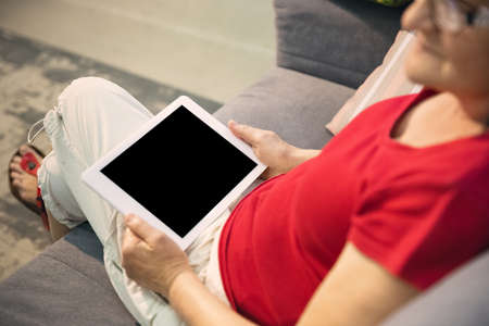 Mature woman spending time being quarantined - caucasians woman using modern gadgets, drinking tea....