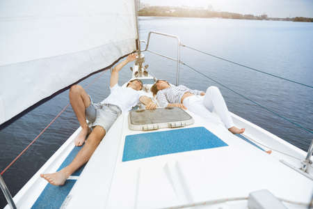 Young cheerful caucasian couple resting at boat party outdoor, smiling and happy. Adventure in sea...