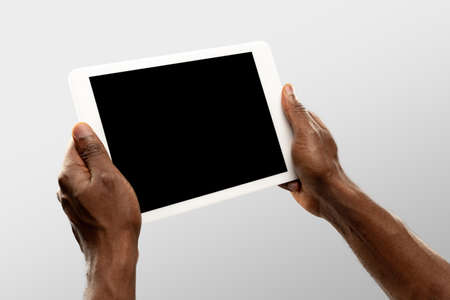 Watching, scrolling. Close up male hands holding tablet with blank screen during online watching of popular sport matches, championships. Copyspace for ad. Devices, gadgets, technologies concept.の写真素材