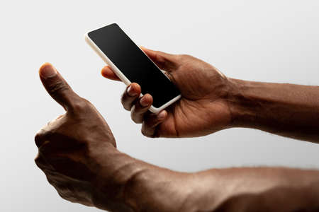 Thumb up, like. Close up male hands holding smartphone with blank screen during online watching of popular sport matches, championships. Copyspace for ad. Devices, gadgets, technologies concept.の写真素材