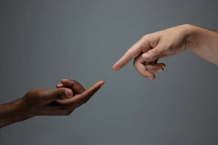 Touching of God. Racial tolerance. Respect social unity. African and caucasian hands gesturing on gray studio background. Human rights, friendship, intenational unity concept. Interracial unity.の写真素材