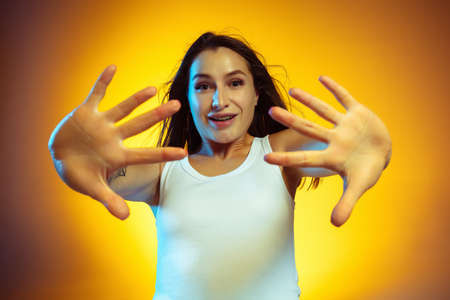 Open palms. Portrait of young caucasian woman isolated on gradient yellow studio background....