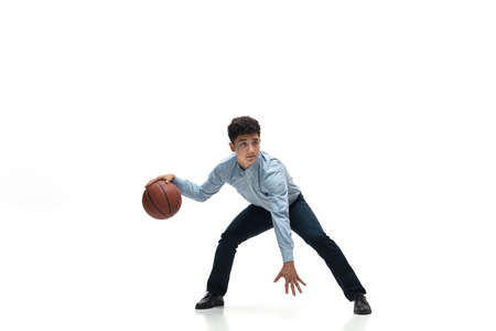 Boss. Man in office clothes playing basketball on white background like professional player, sportsman. Unusual look for businessman in motion, action with ball. Sport, healthy lifestyle, creativity.の写真素材