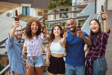 Group of happy friends having beer party in summer day. Resting together outdoor, celebrating and relaxing, laughting. Summer lifestyle, friendship concept. Cheer with beers bottles, cheerful, happy.の写真素材