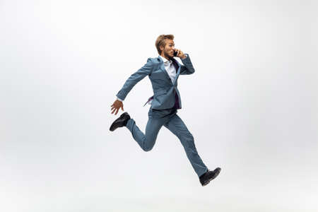 Deals. Man in office clothes running, jogging on white background like professional athlete,...