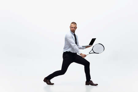 Time for movement. Man in office clothes plays tennis isolated on white studio background. Businessman training in motion, action. Unusual look for sportsman, new activity. Sport, healthy lifestyle.の写真素材