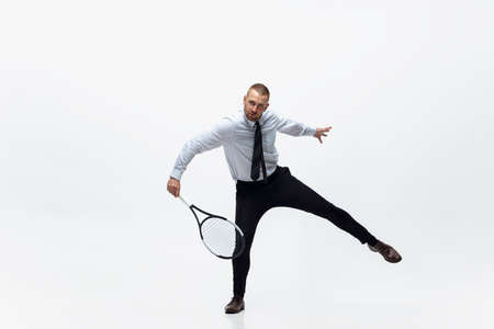Time for movement. Man in office clothes plays tennis isolated on white studio background. Businessman training in motion, action. Unusual look for sportsman, new activity. Sport, healthy lifestyle.の写真素材