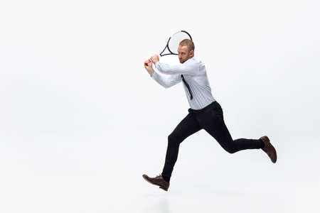Time for movement. Man in office clothes plays tennis isolated on white studio background. Businessman training in motion, action. Unusual look for sportsman, new activity. Sport, healthy lifestyle.の写真素材