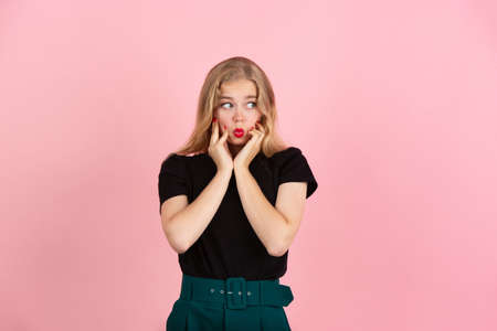 Shy, asking. Portrait of young emotional woman gesturing isolated on pink studio background. Human...