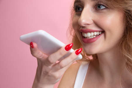 Recording voice message. Caucasian young womans portrait isolated on pink studio background....