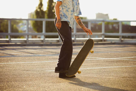 Skateboarder doing a trick at the citys street, close up moments. Young man in sneakers and cap...