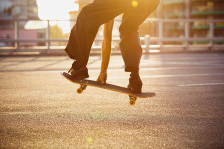 Skateboarder doing a trick at the citys street, close up moments. Young man in sneakers and cap...