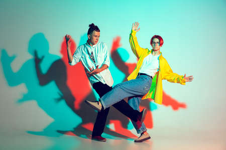 Young man and woman, couple dancing hip-hop, street style isolated on studio background in colorful...