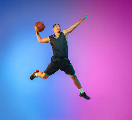 Winner. Young basketball player in action, motion in high jump on gradient background in neon....