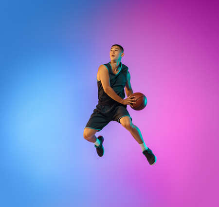 Winner. Young basketball player in action, motion in high jump on gradient background in neon....