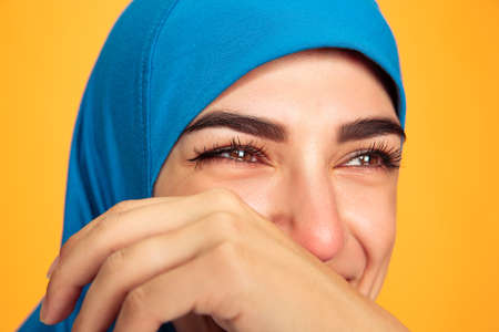 Laughting. Close up young muslim woman isolated on yellow studio background. Stylish, trendy. Human...