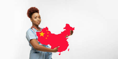 Beautiful african-american doctor cares about China isolated over white studio background. Copyspace. Concept of healthcare and medicine, taking care, treatment during  outbreak, pandemic.の写真素材