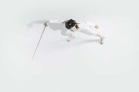 First. Teen girl in fencing costume with sword in hand on white background. Top view. Young female...