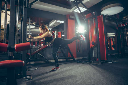 Concentrate. Young muscular caucasian woman practicing in gym with equipment. Athletic female model...