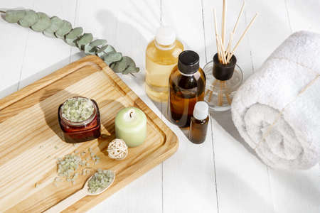 Beautiful spa composition on massage table in wellness center, copyspace. Accessories for relaxing treatments and personal care. Towels, oils, serum, sea salts and scrubs. Decorative candles.の写真素材